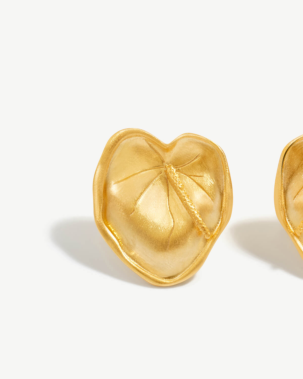 a pair of gold heart shaped earrings on a white background