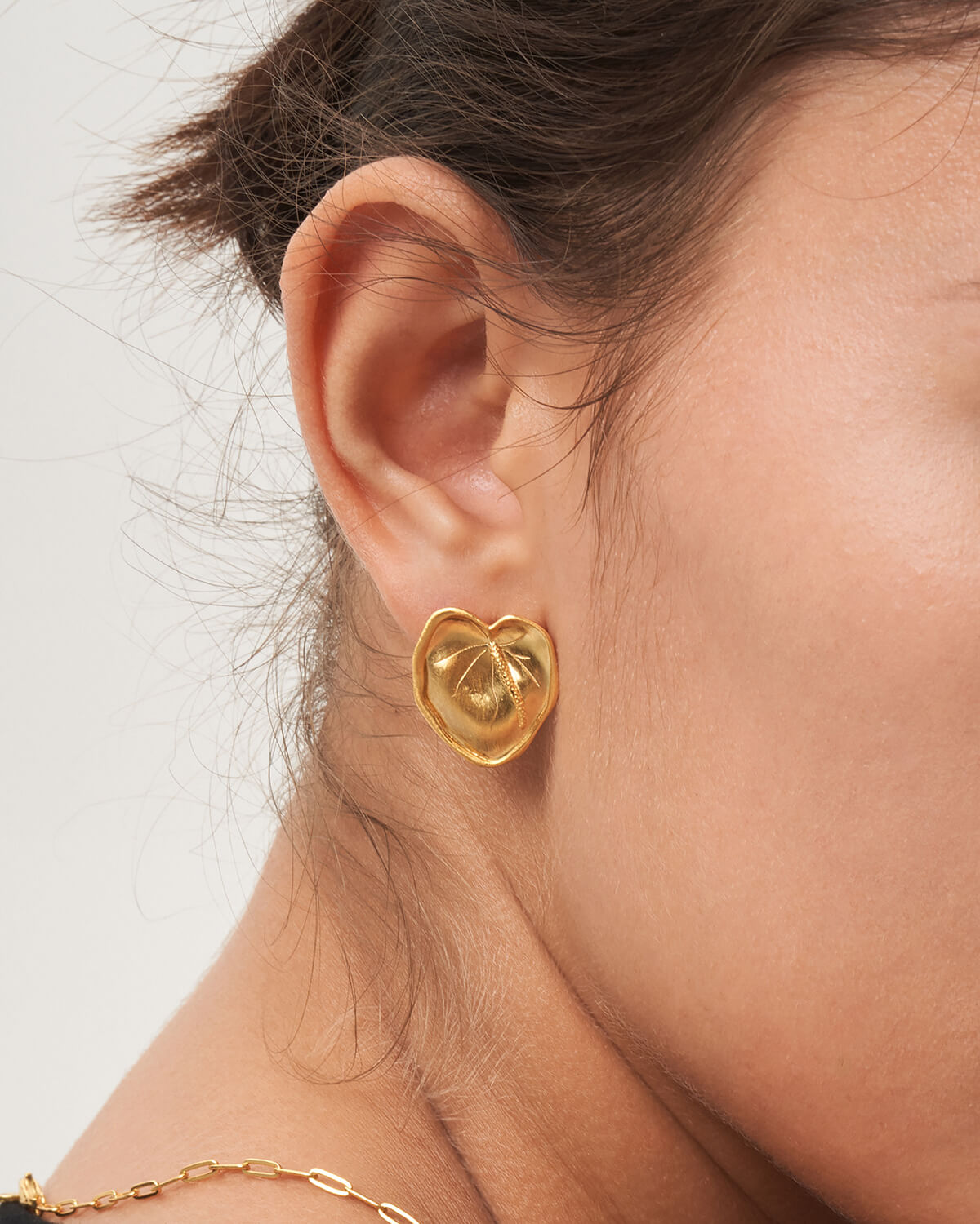 a close up of a person wearing a gold earring